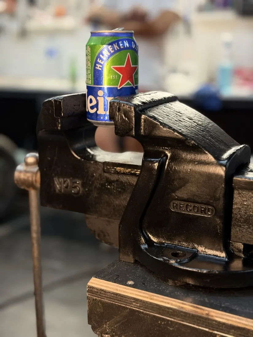 A can of beer clamped in a black Record No. 5 bench vise