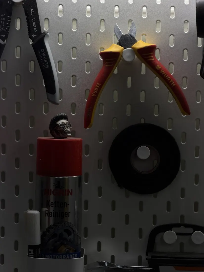 Pliers and cutters hanging on a pegboard next to a can of chain cleaner