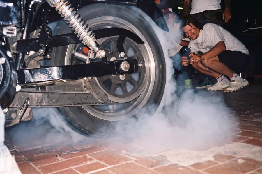 A burnout on the brick floor, a friend crouching in the tyre smoke to film it
